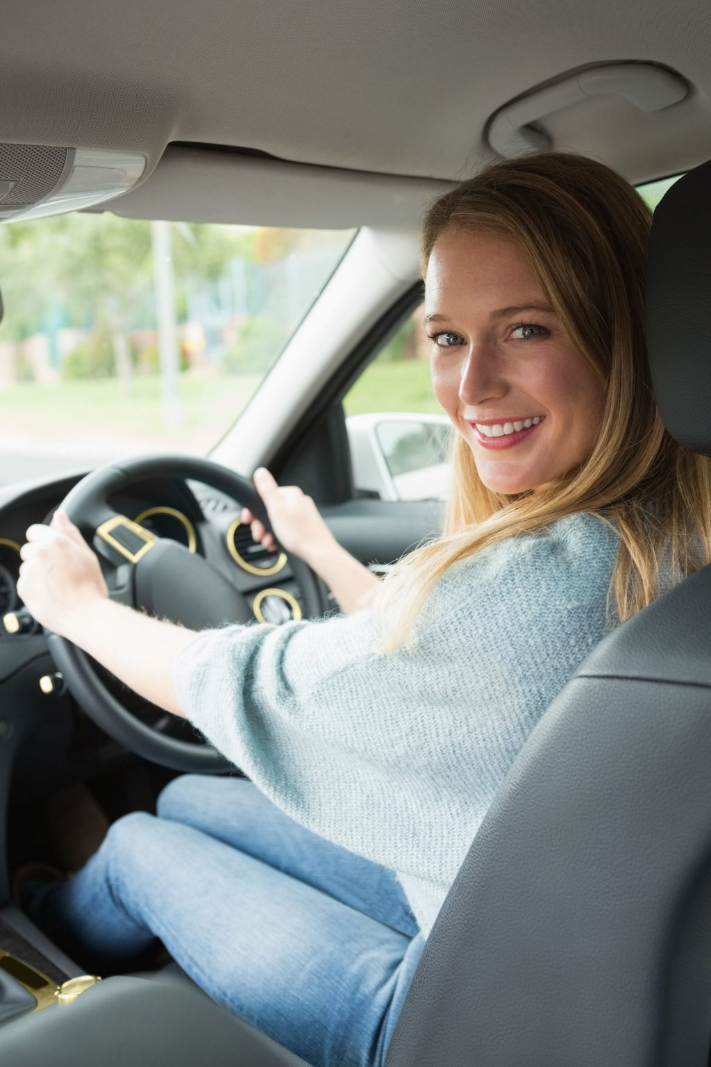 Young woman smiling while driving in her car